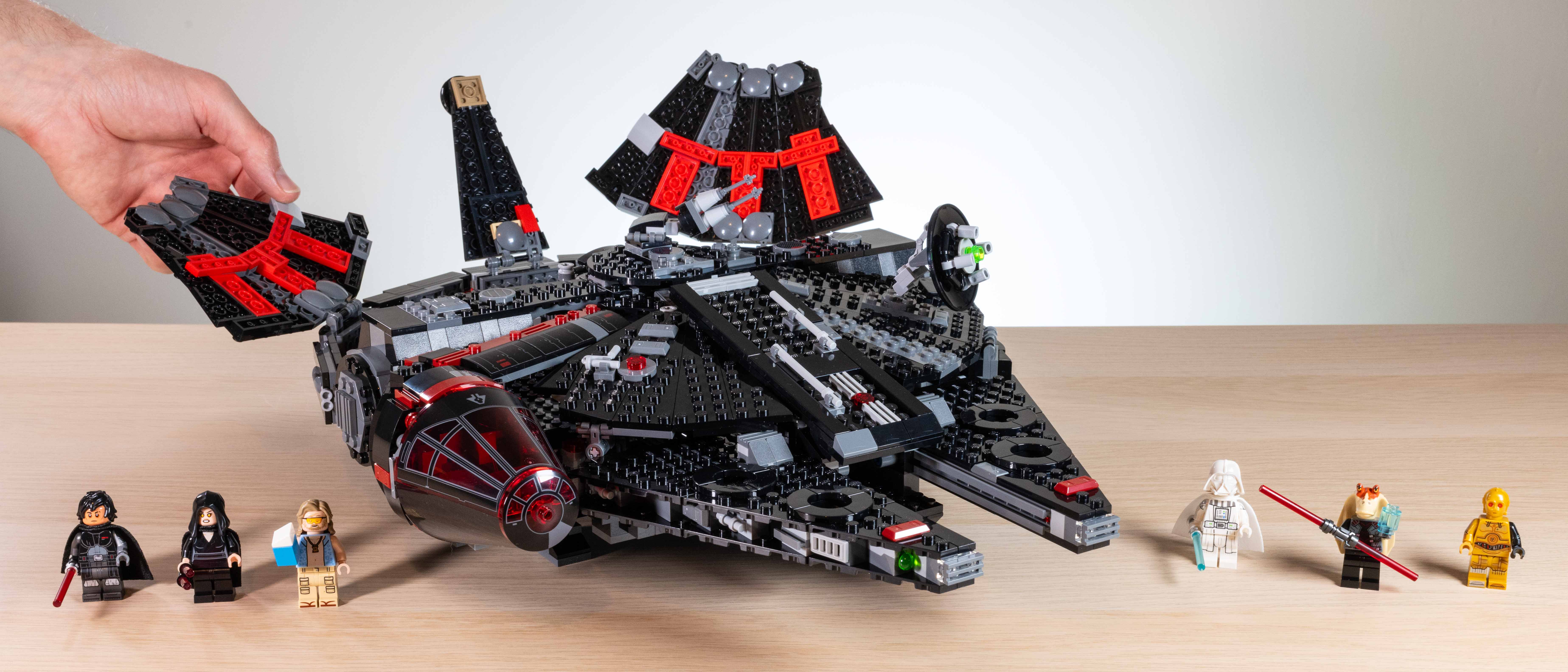 Lego Star Wars The Dark Falcon (75389) hand opening flaps, surrounded by Minifigures on a wooden surface in front of a neutral background 