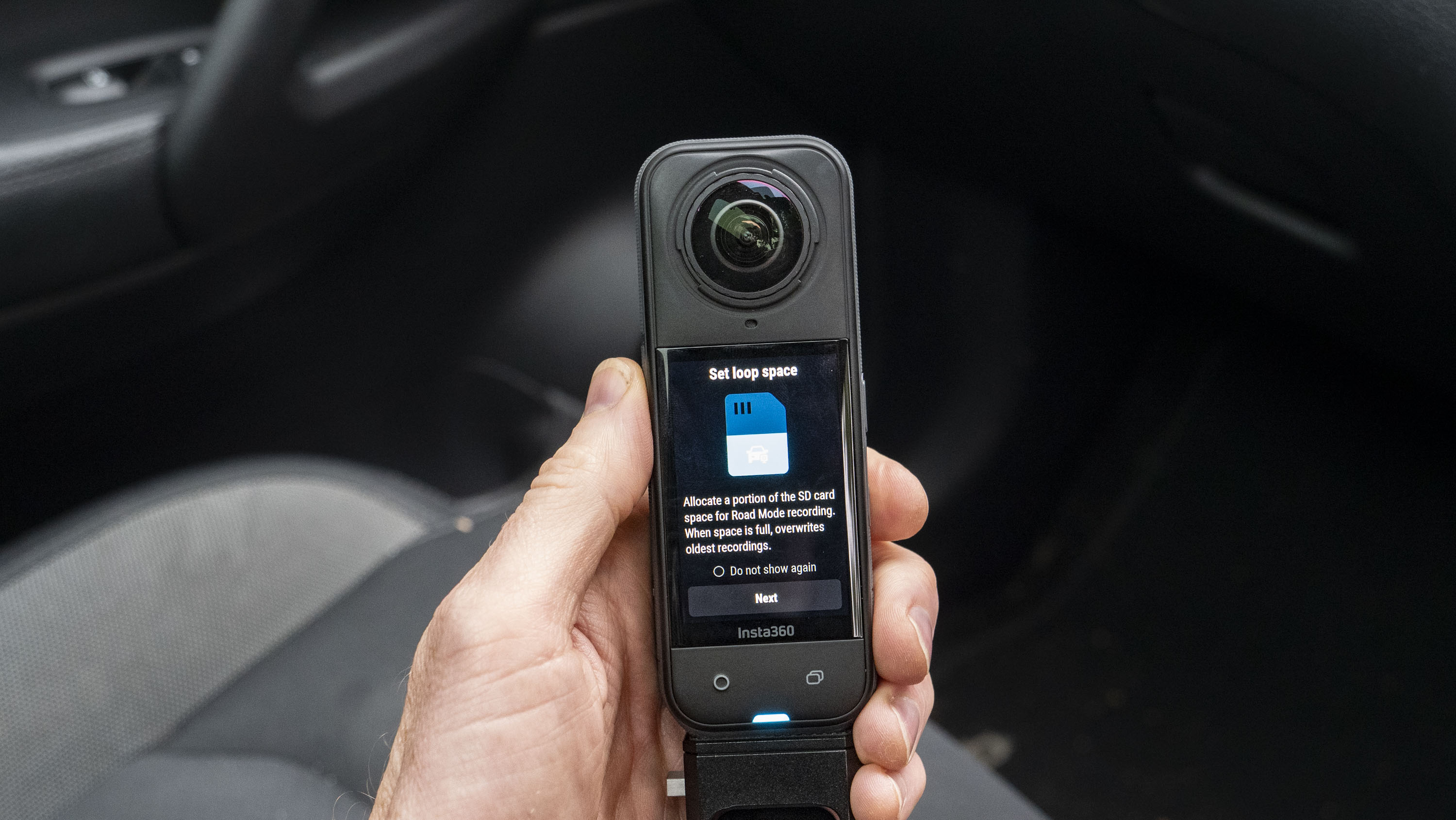 Insta360 X5 inside a car in user's hand, with loop recording options on the display
