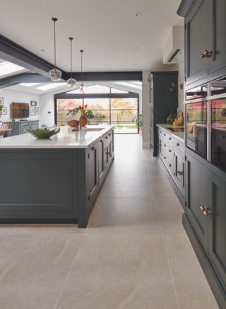 Kitchen with green painted cabinetry, island, neutral walls and floor tiles