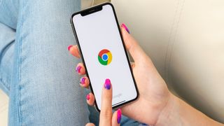 En kvinne ligger i en sofa og bruker Google Chrome på en smarttelefon