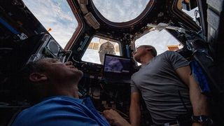 NASA astronauts (from left) Thomas Marshburn and Mark Vande Hei gaze out the station's cupola windows at Earth below in 2022.