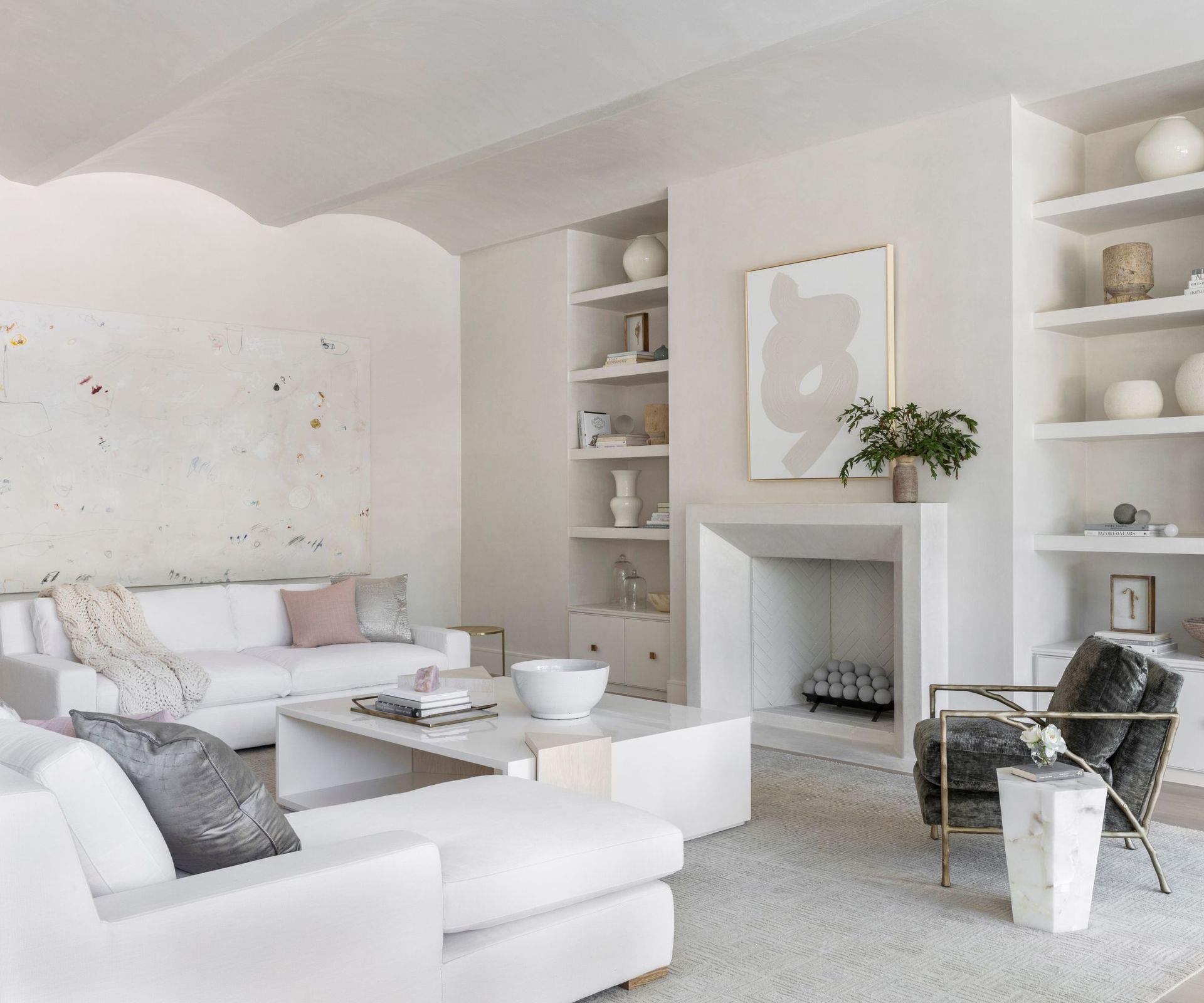 white living room with white corner sofa, white modern coffee table, white walls and built-in shelving with neutral decorative objects