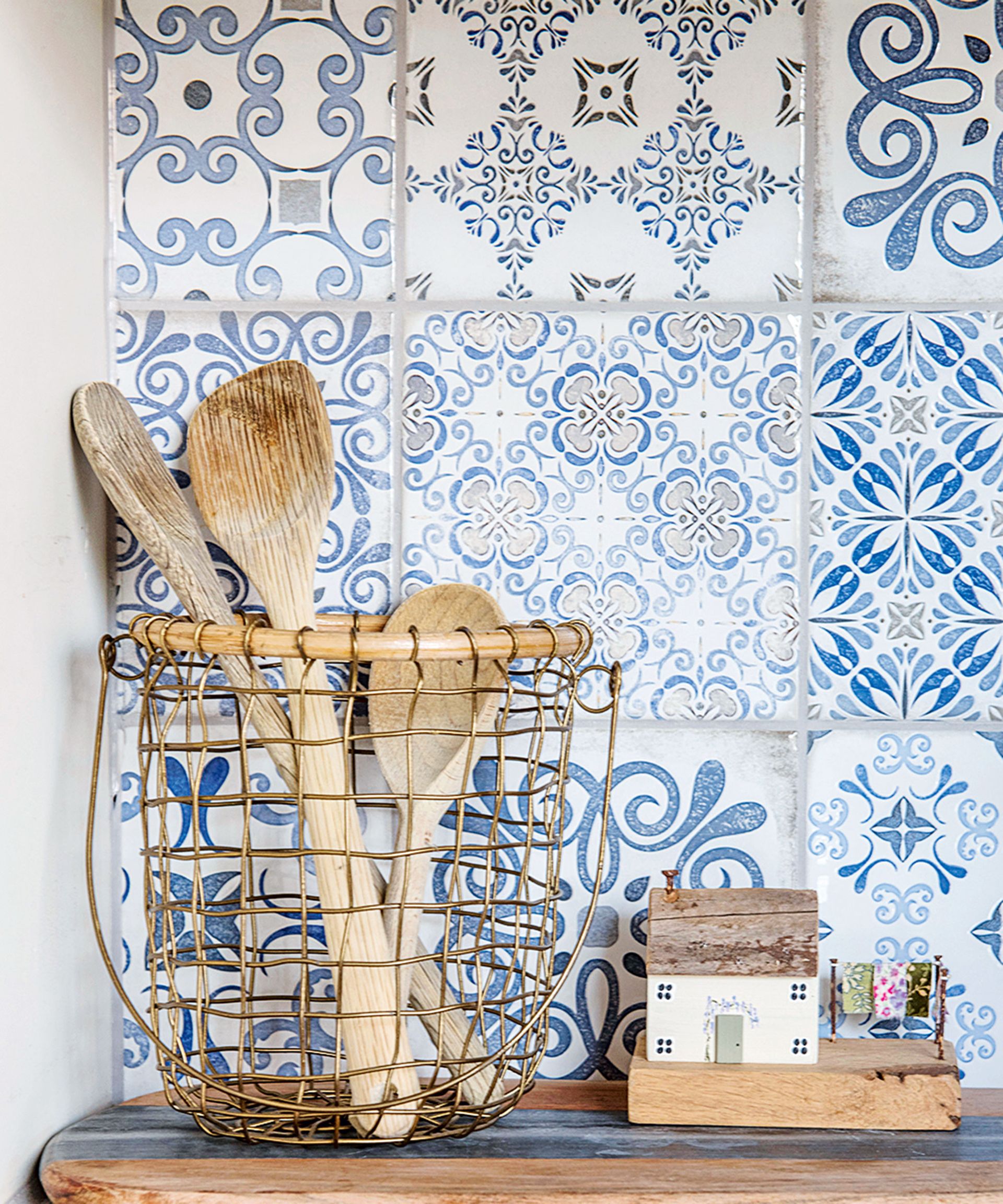Blue and white patterned kitchen wall tiles behind a pot of utensils