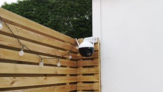 The Ezviz C8C mounted to a wooden fence in a garden