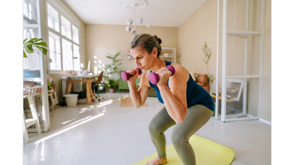 Woman squatting with a pair of dumbbells.