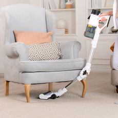 White cordless vacuum cleaning under armchair
