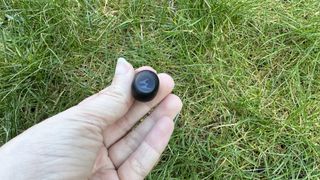 Someone holding one of the Motorola Moto Buds 150 against the grass.