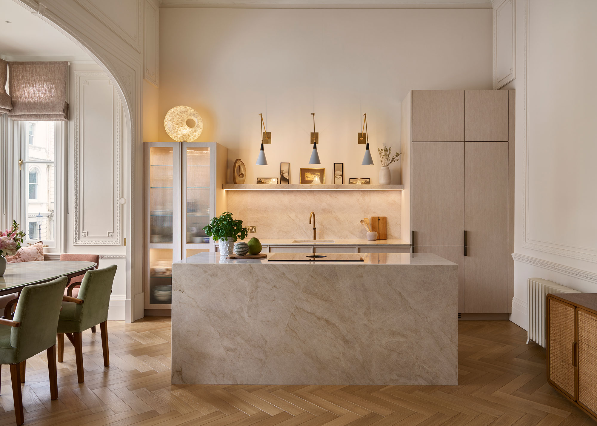 neutral stone kitchen diner with wall sconces as well as an island in the middle with an induction hob on top of it