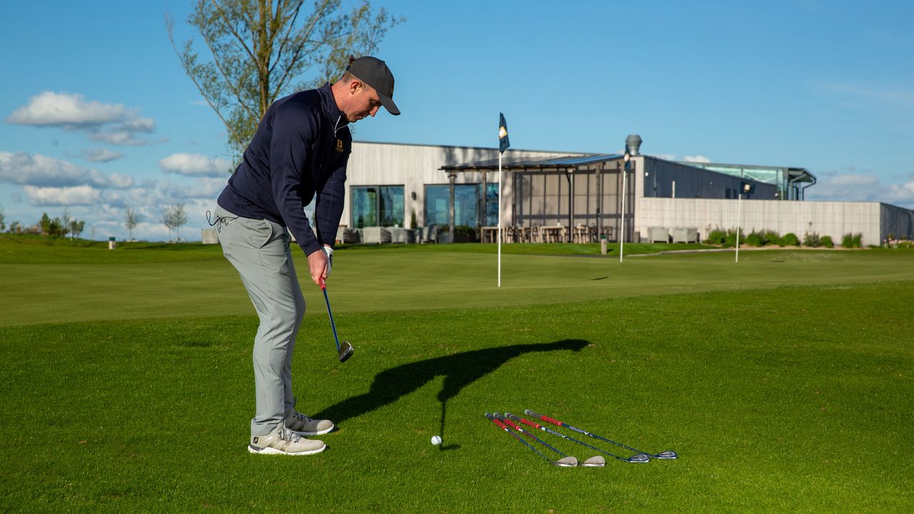 PGA pro John Howells hitting a chip shot at the short game area at JCB Golf Club