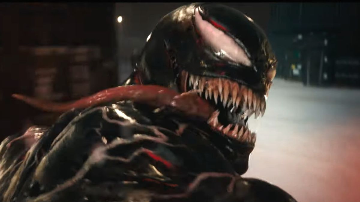 Venom looks back with his tongue hanging out while driving a motorcycle in Venom: The Last Dance.