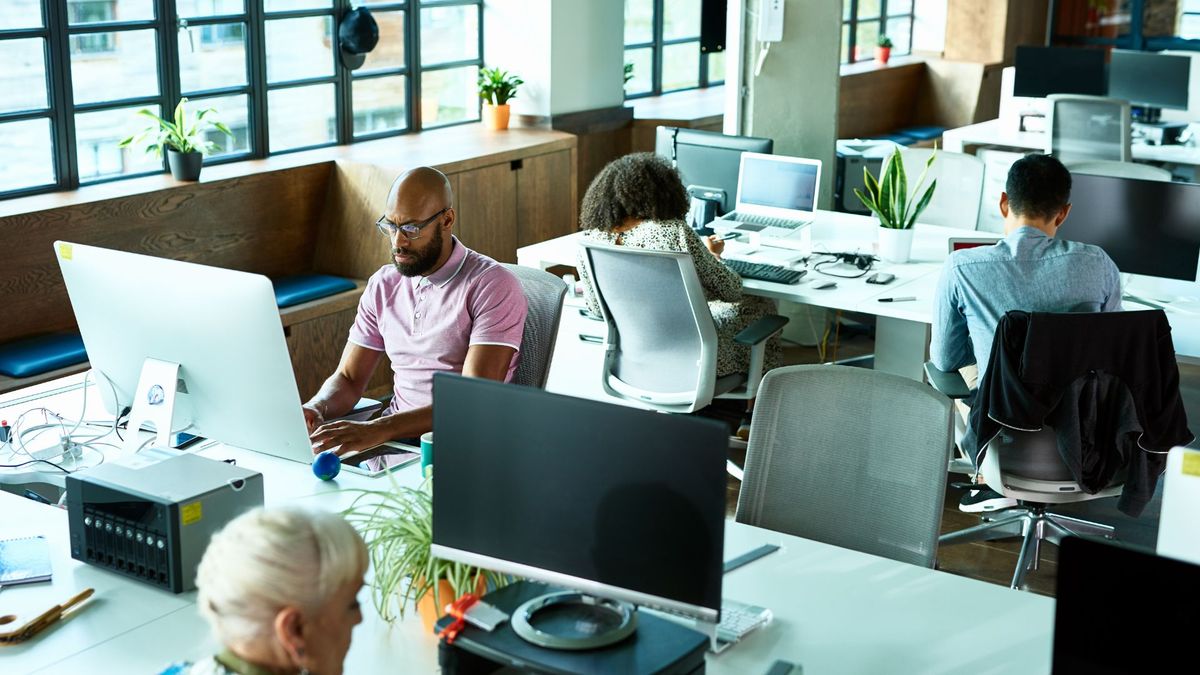 Open plan office space with workers sitting at desks working on computers.