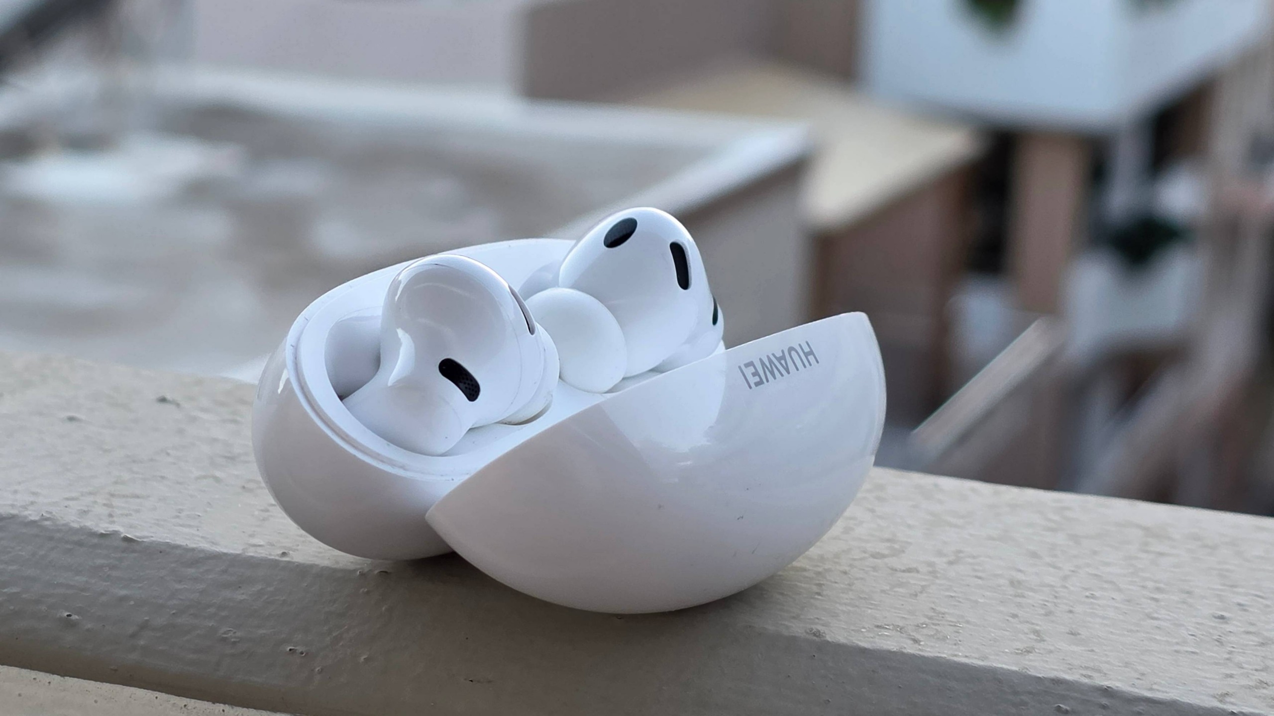 The Huawei FreeBuds Neo buds in their case on a ledge, in front of a city.