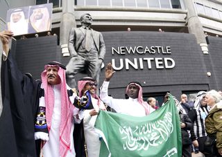 Newcastle fans outside the stadium hold up a Saudi Arabia flag