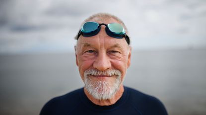 A man wearing swimming goggles smiles.