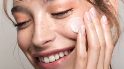 Model applying milky skincare products to her face