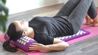 a photo of a woman lying on an acupressure mat