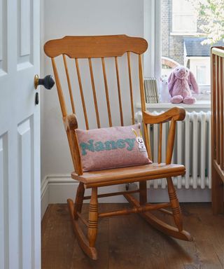 A traditional wooden rocking chair with personalized pink cushion with blue applique