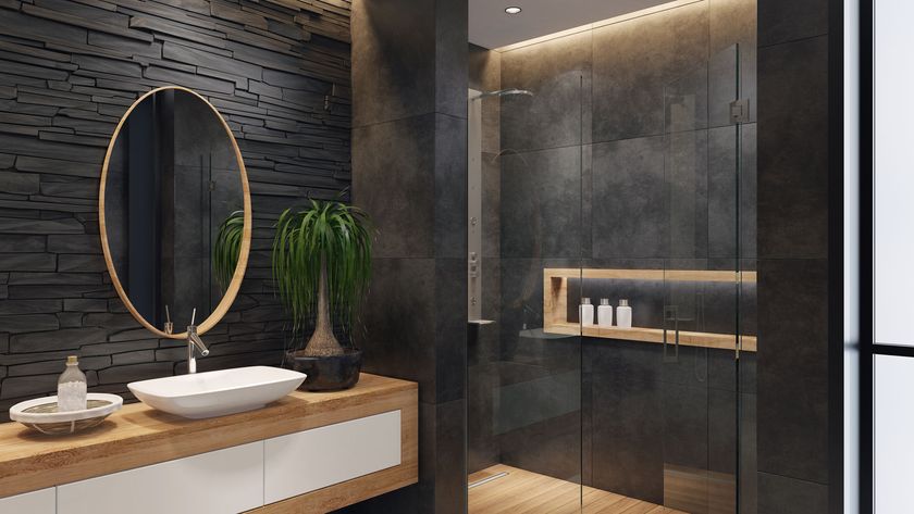 Dark tiled bathroom with glass walk-in shower and wooden furniture