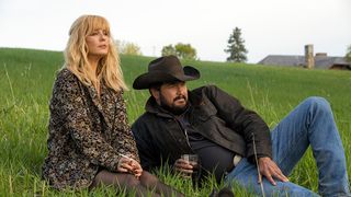 Kelly Reilly as Beth Dutton and Cole Hauser as Rip Wheeler sit in the grass on Yellowstone season 5