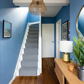 blue painted hallway with stairs and striped runner