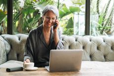 Woman with grey hair in casual clothes working at laptop