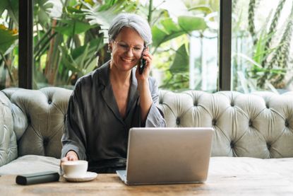 Woman with grey hair in casual clothes working at laptop