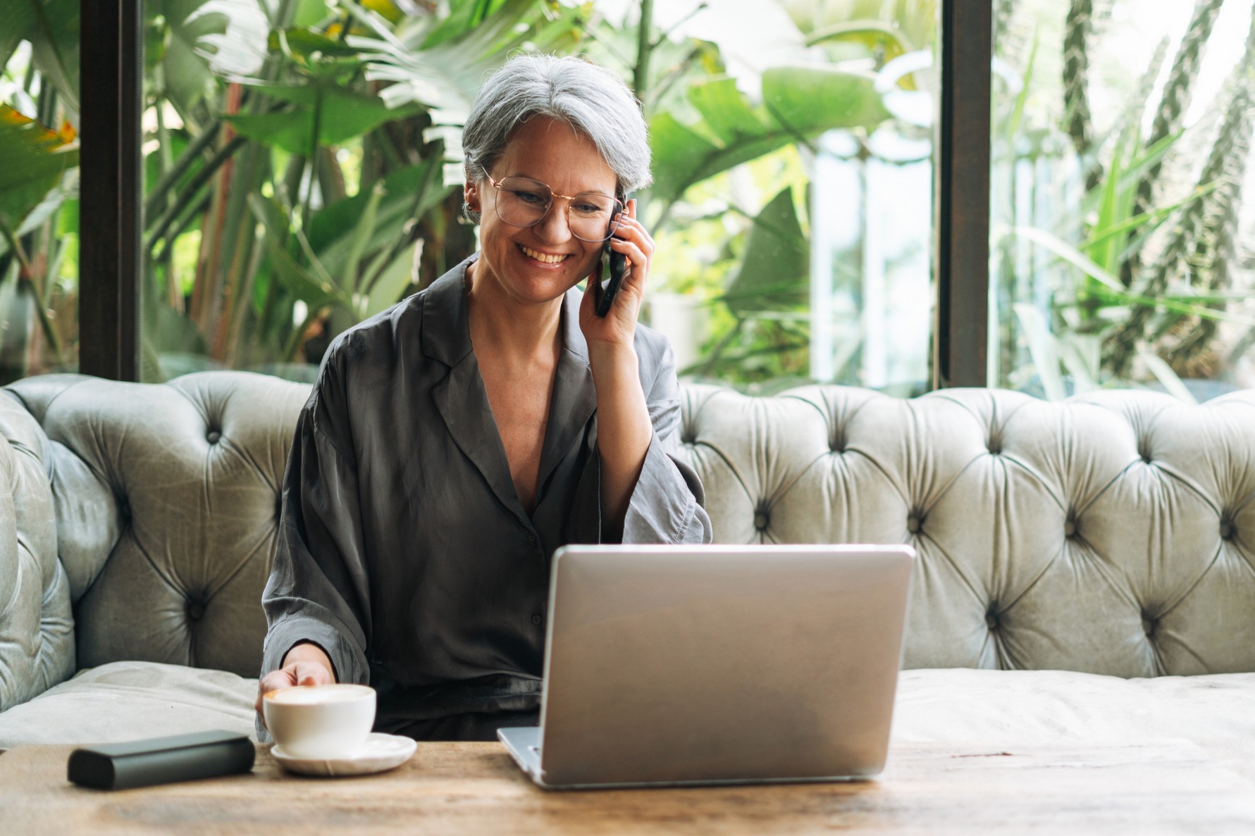 Woman with grey hair in casual clothes working at laptop