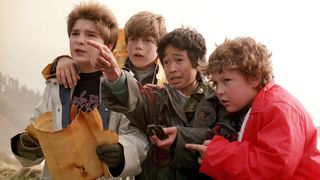 A still from the movie The Goonies in which all the main child stars are looking at a map and pointing off camera.