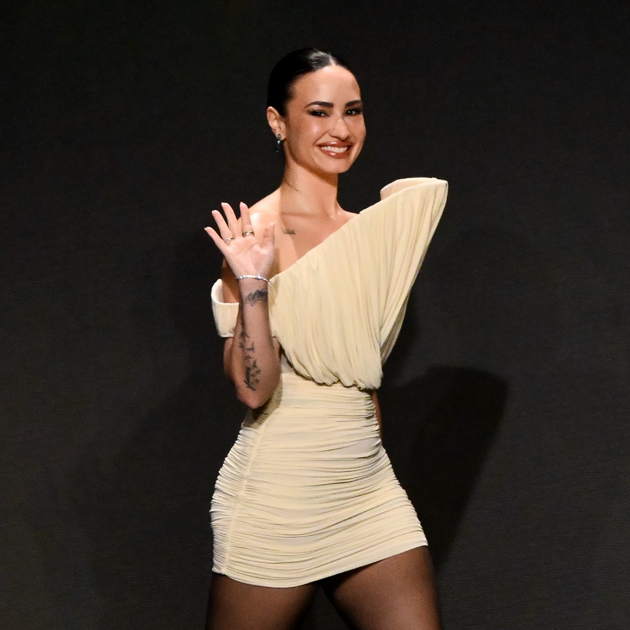 a woman wearing a beige mini dress in front of a black background