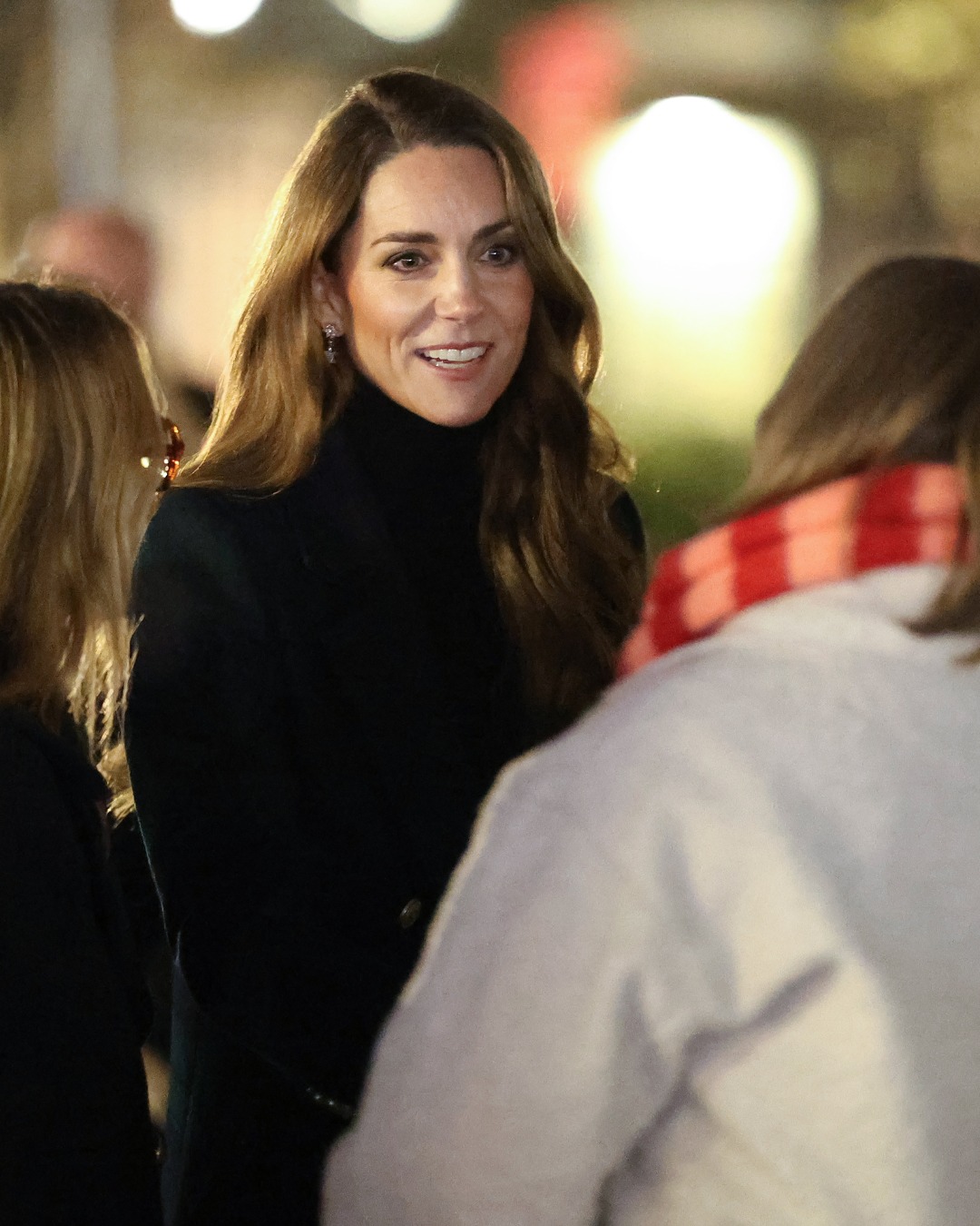Kate Middleton wearing a plaid coat talking to a woman