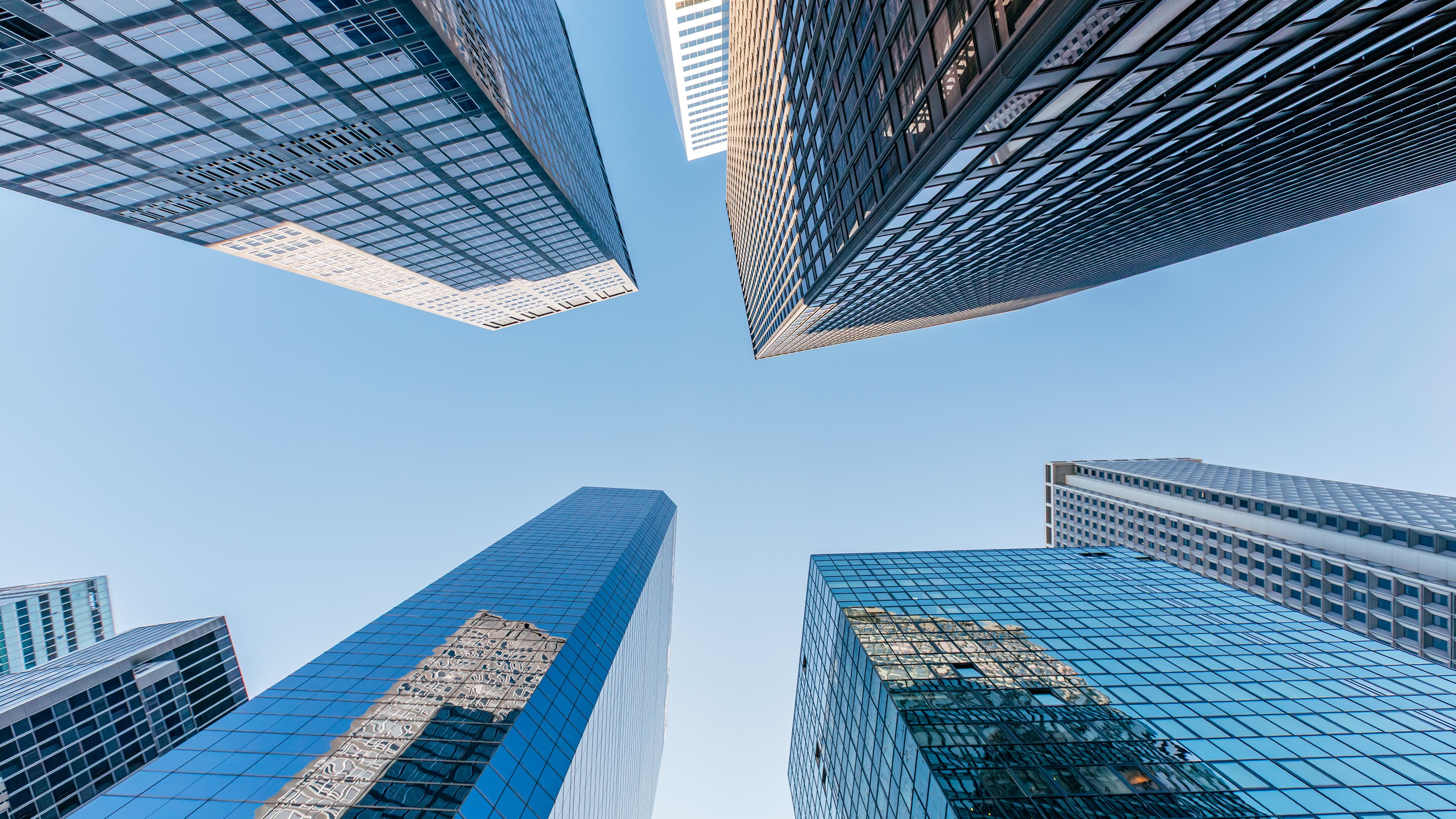 Looking up at skyscrapers in New York City against a blue sky.