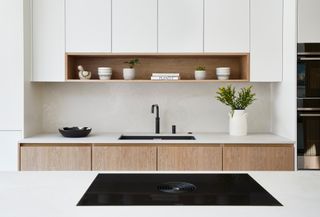 a white and wood kitchen with a hob with downdraught extraction