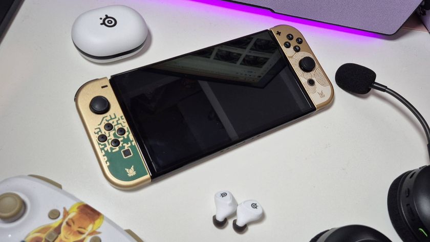 Image of the Nintendo Switch OLED on a table with a headset and gaming earbuds siting around it, taken by writer Rosalie Newcombe.