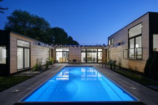 rectangular pool at night lit up with outdoor lighting