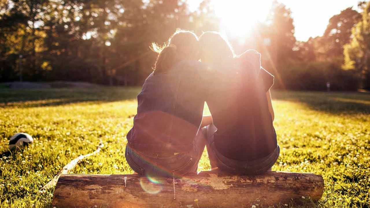 A happy couple sits together on a log in the woods