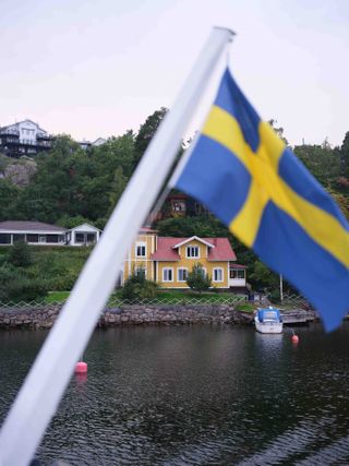 House along the edge of the river obscured by Swedish flag