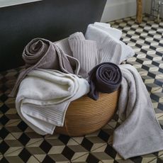 grey and white towels in brown round bucket on designed flooring