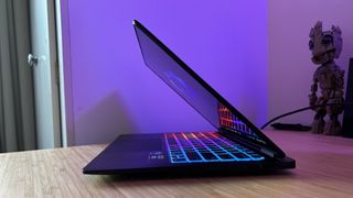HP Omen Transcend 14 gaming laptop half closed on a wooden desk with RGB lighting and display on