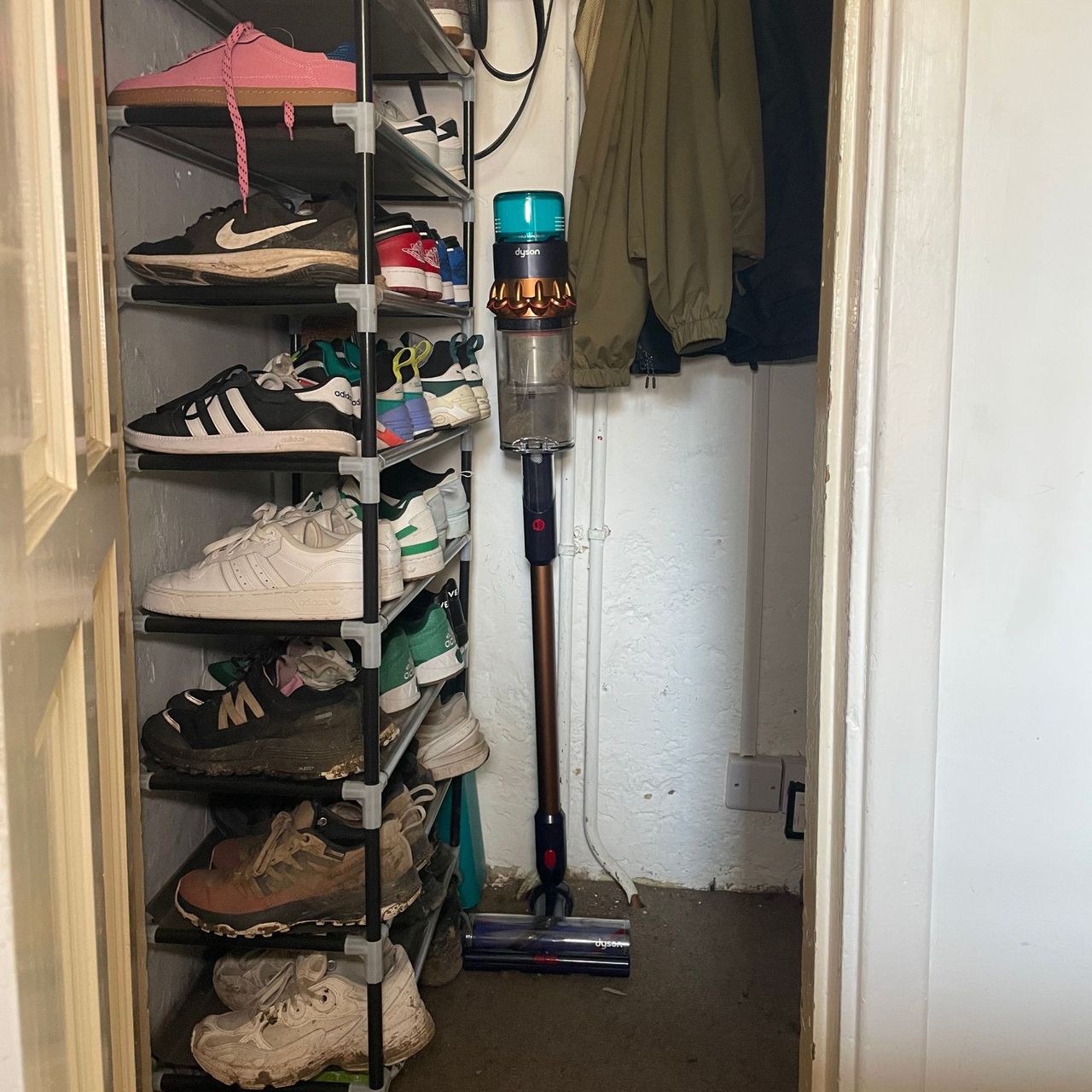 Dyson Gen5detect vacuum stored in an under-the-stairs cupboard next to a shoe rack