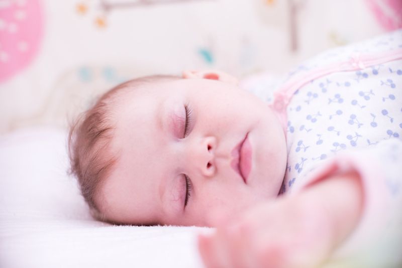 A baby sleeps on her back.