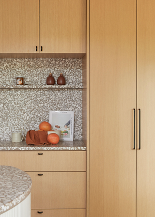 Terrazzo backsplash and counter in grey with pale wooden cabinets