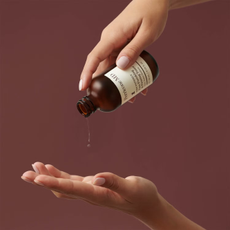 Perricone MD bottle pouring liquid onto hand, with brown background