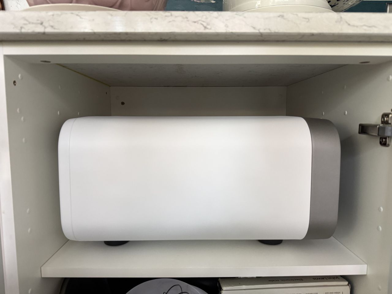 A side view of Ooni's volt 2 pizza oven in polar white fitted inside of a kitchen cupboard