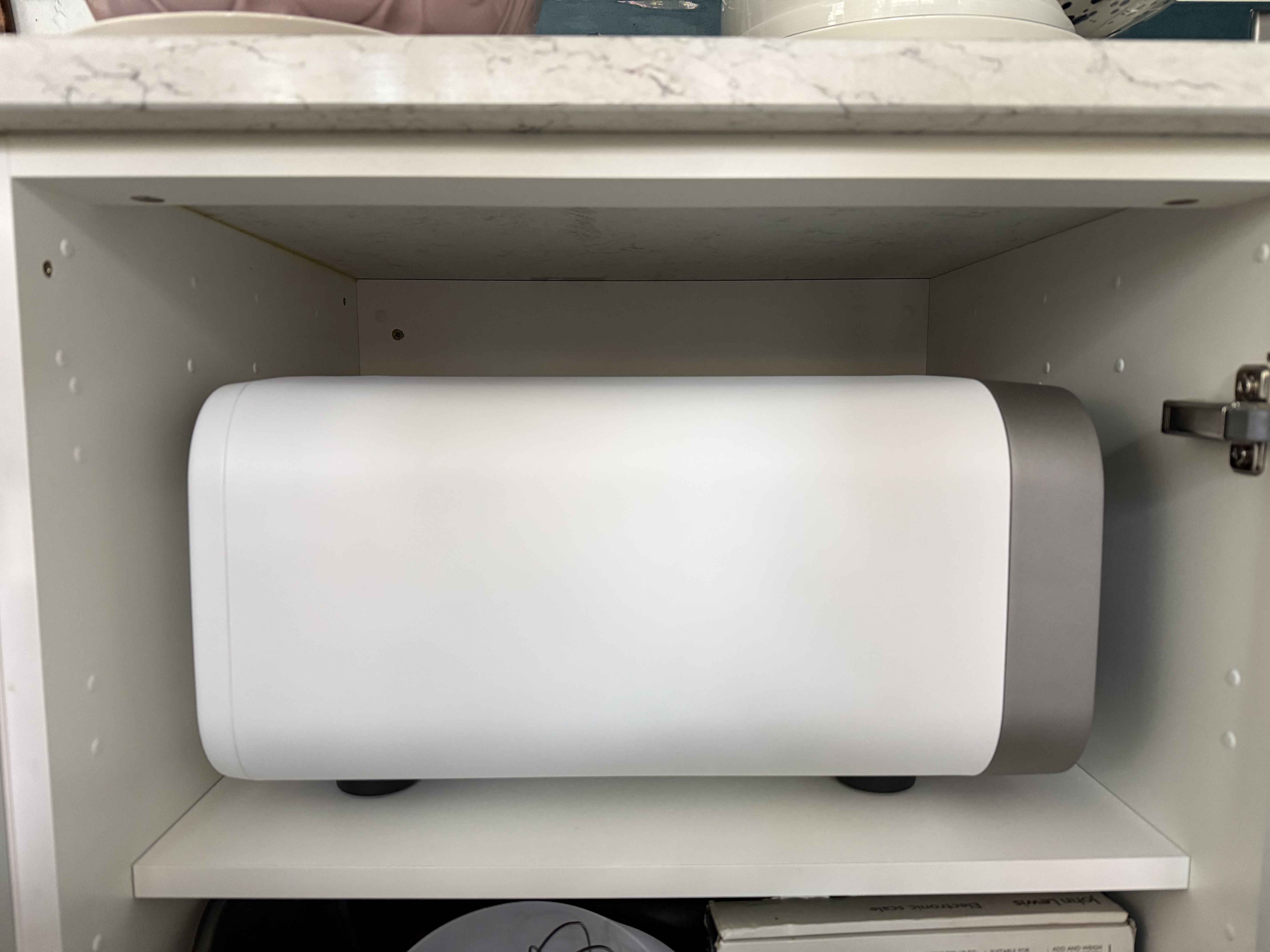 A side view of Ooni's volt 2 pizza oven in polar white fitted inside of a kitchen cupboard