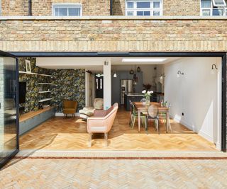 brick rear extension on terraced property housing kitchen, living and dining area with herringbone laid wooden flooring matching the brick laid patio outside