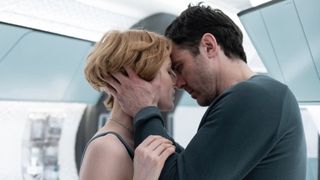 A man and woman embrace aboard a sterile spaceship