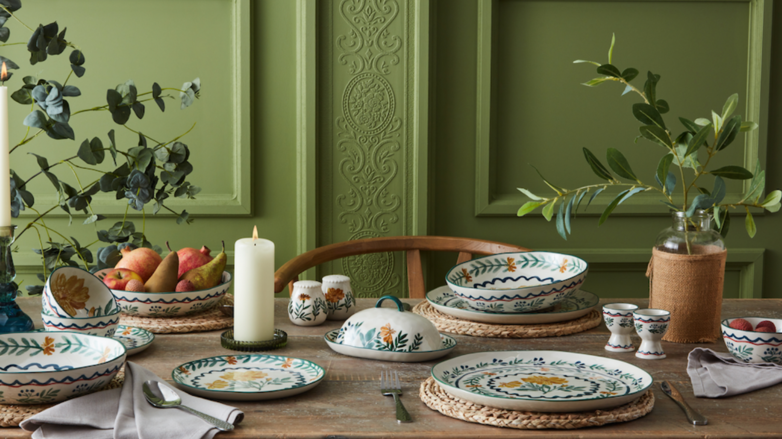 Nutmeg Dark Orchid collection on a dining table with a green, period wall as a backdrop.