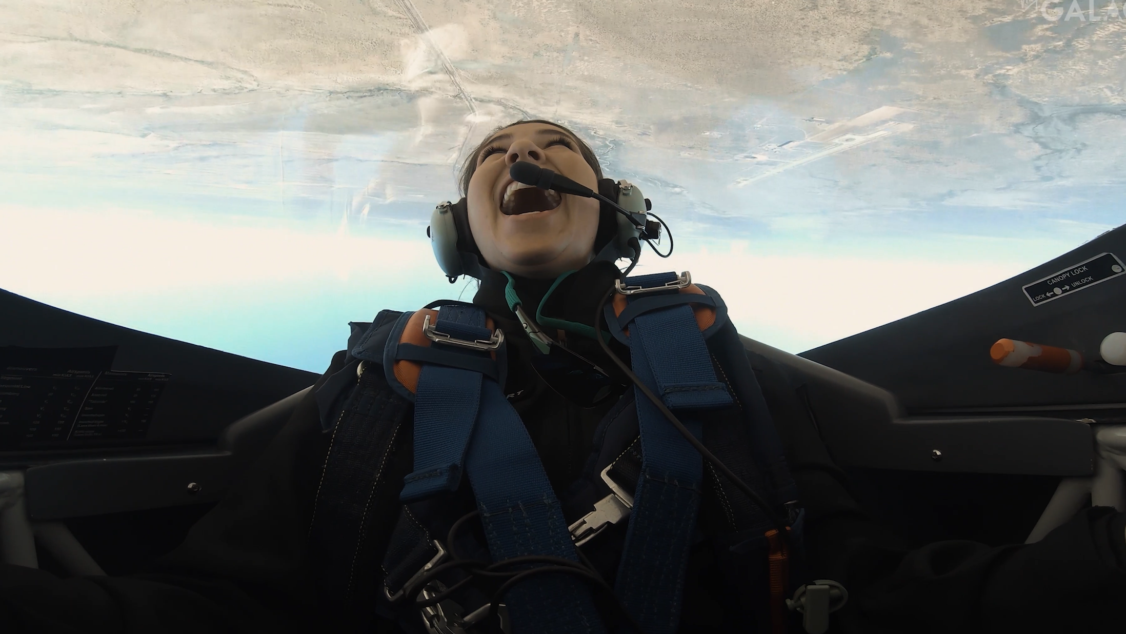 jamila gilbert in an upside-down cockpit with bubble shelter above and the ground visible in the window