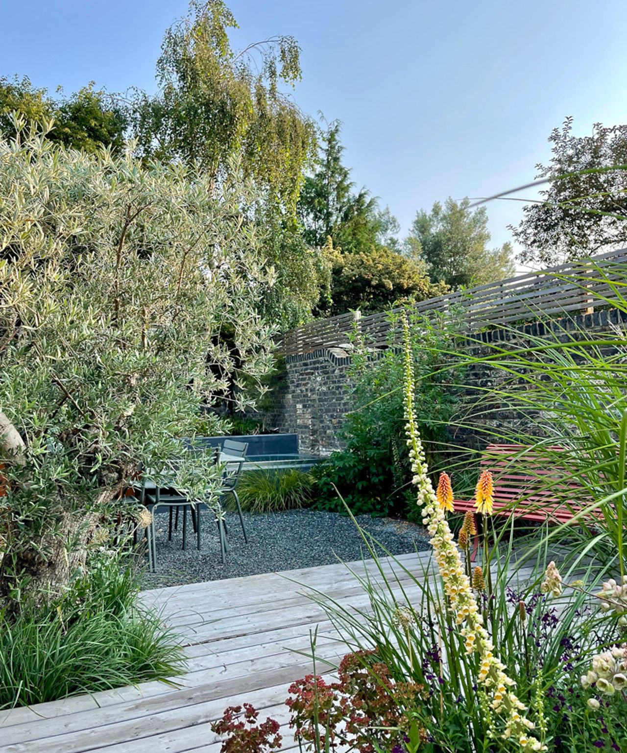 garden with wooden decking and gravel and red hot pokers