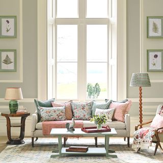 living room with cream sofa ressed with pink and blue cushions and standard lamp
